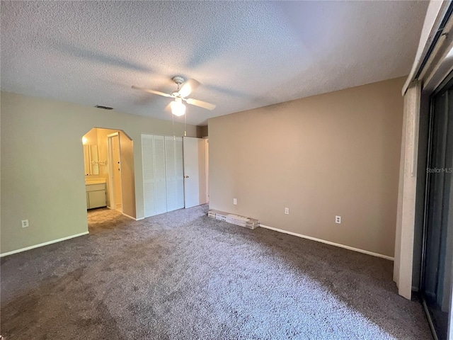 25068 Harborview Rd Unit 1A, Punta Gorda, FL 33980 - unfurnished bedroom with arched walkways, carpet, a textured ceiling, baseboards, and ceiling fan