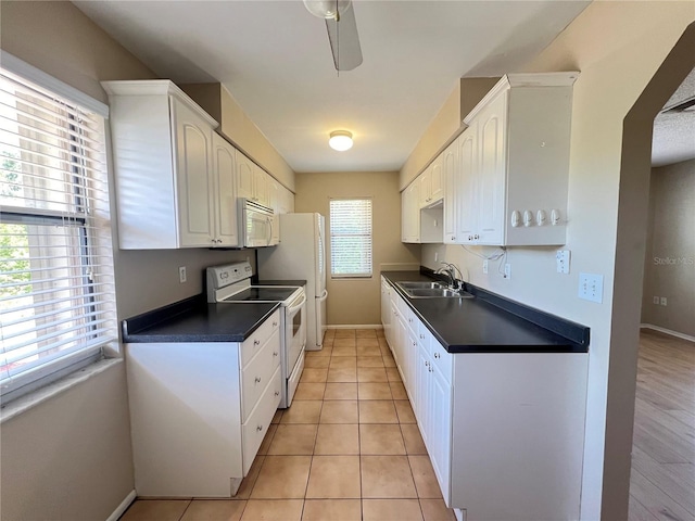25068 Harborview Rd Unit 1A, Punta Gorda, FL 33980 - kitchen with white appliances, a sink, dark countertops, white cabinets, and baseboards
