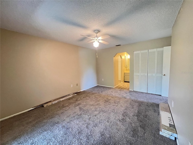 25068 Harborview Rd Unit 1A, Punta Gorda, FL 33980 - unfurnished bedroom featuring arched walkways, carpet flooring, a textured ceiling, a ceiling fan, and baseboards