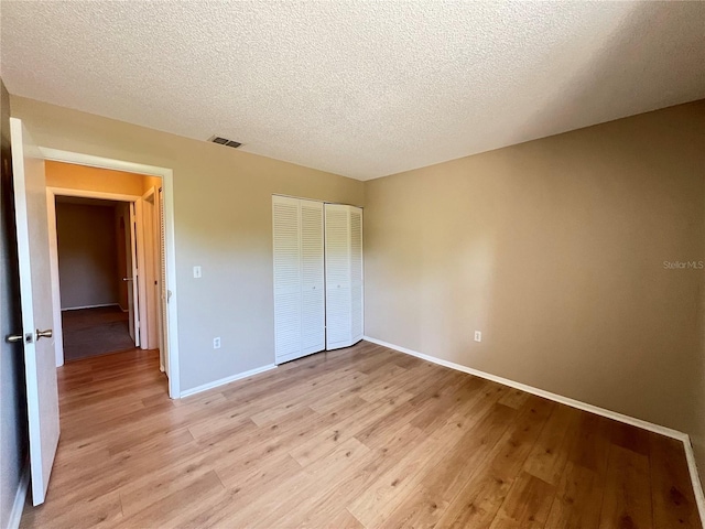 25068 Harborview Rd Unit 1A, Punta Gorda, FL 33980 - unfurnished bedroom featuring light wood-style floors, baseboards, a closet, and a textured ceiling