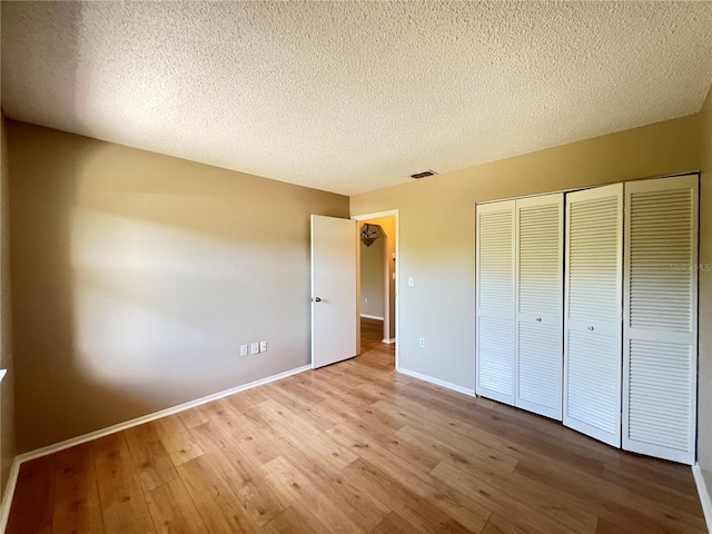 25068 Harborview Rd Unit 1A, Punta Gorda, FL 33980 - unfurnished bedroom with wood finished floors, a closet, a textured ceiling, and baseboards