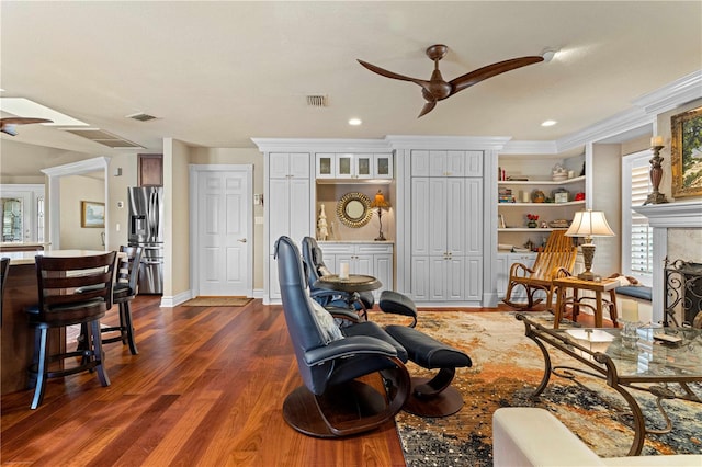 living room with crown molding, ceiling fan, and dark wood-type flooring