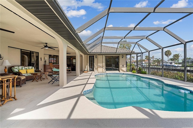 view of pool with glass enclosure, ceiling fan, an outdoor hangout area, and a patio