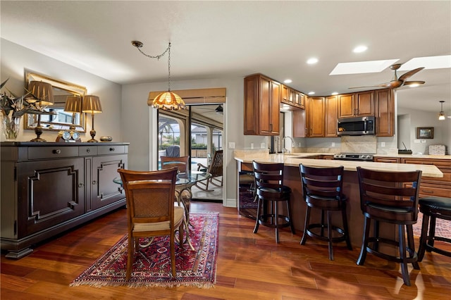 kitchen with dark wood-type flooring, sink, a skylight, kitchen peninsula, and stainless steel appliances