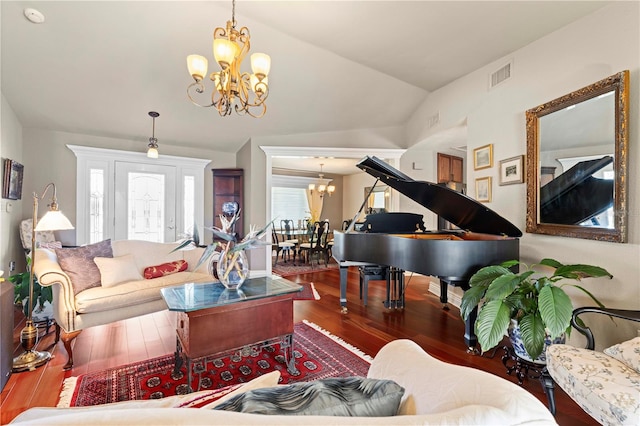 living room featuring an inviting chandelier, vaulted ceiling, and hardwood / wood-style flooring