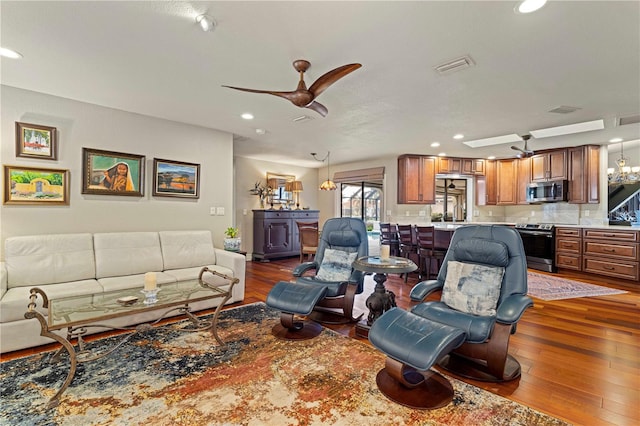 living room featuring ceiling fan with notable chandelier and dark hardwood / wood-style flooring