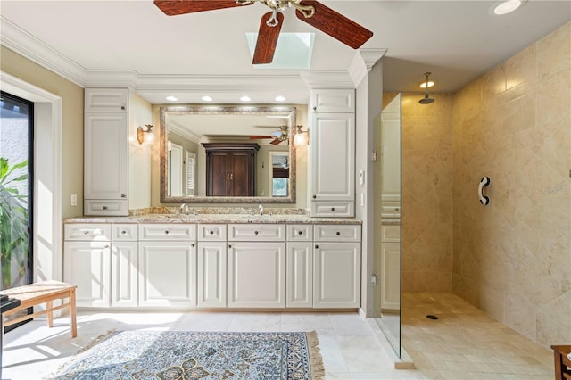 bathroom with a tile shower, vanity, crown molding, and ceiling fan