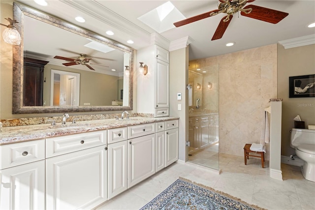 bathroom featuring toilet, a skylight, a tile shower, ornamental molding, and vanity