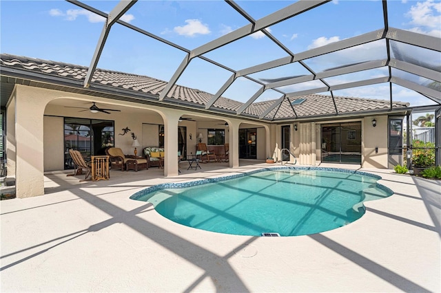 view of swimming pool with a patio, ceiling fan, and glass enclosure