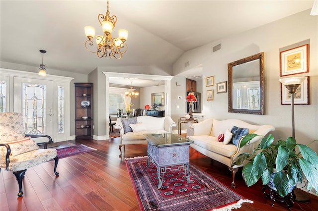 living room featuring lofted ceiling, dark wood-type flooring, a wealth of natural light, and an inviting chandelier