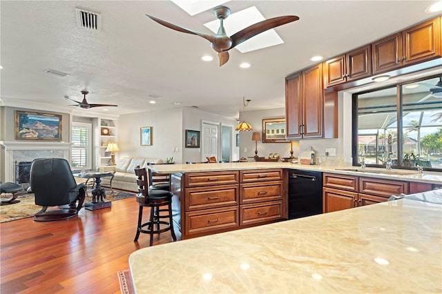 kitchen with pendant lighting, ceiling fan, a kitchen breakfast bar, a fireplace, and wood-type flooring