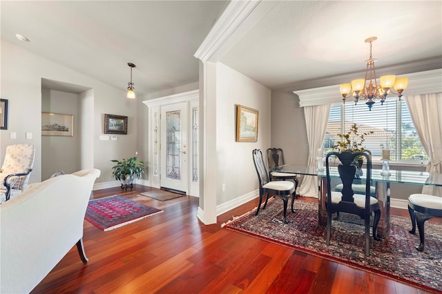 dining area featuring hardwood / wood-style flooring, vaulted ceiling, and an inviting chandelier