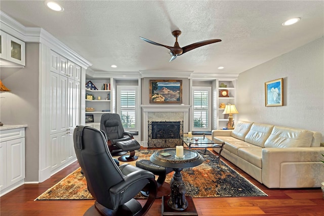 living room featuring built in shelves, dark hardwood / wood-style flooring, a textured ceiling, and a wealth of natural light