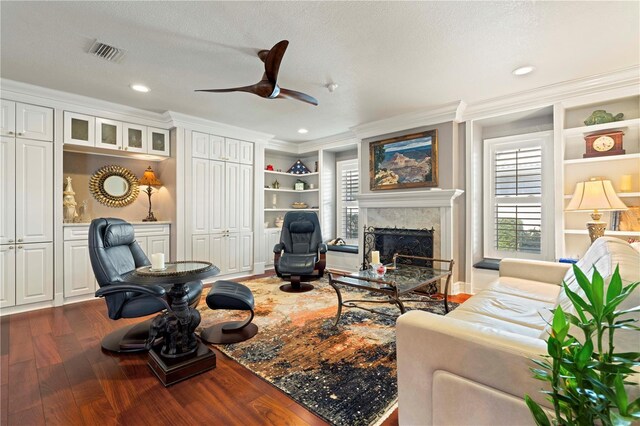 living room with ornamental molding, hardwood / wood-style floors, a high end fireplace, and built in shelves