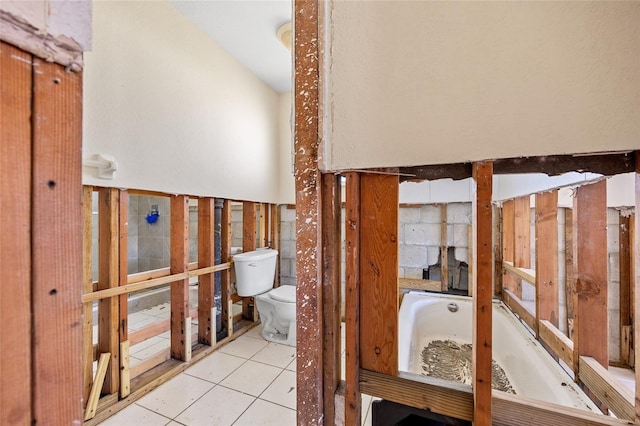 bathroom with toilet, a tub to relax in, and tile patterned floors