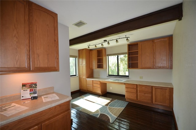 kitchen with rail lighting, built in desk, and dark wood-type flooring