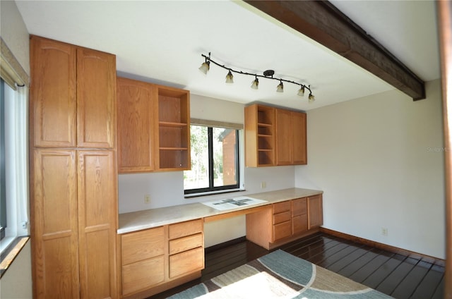 kitchen with dark hardwood / wood-style flooring, built in desk, rail lighting, and beam ceiling