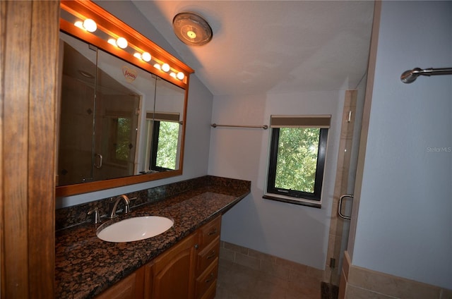 bathroom with tile patterned flooring, vanity, vaulted ceiling, and a shower with door