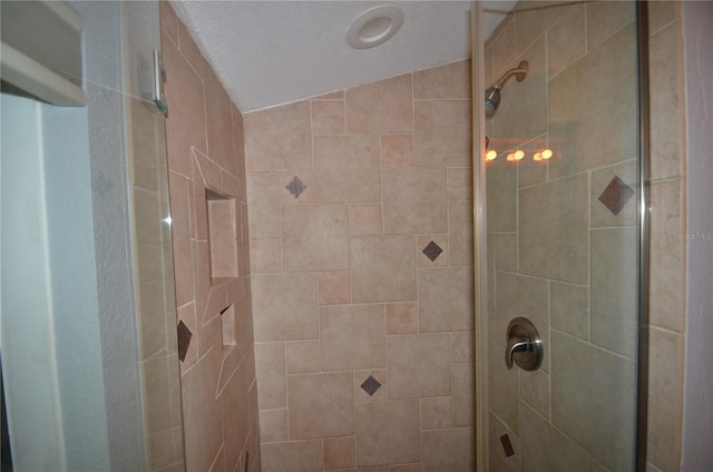 bathroom featuring a textured ceiling, a shower with shower door, and lofted ceiling