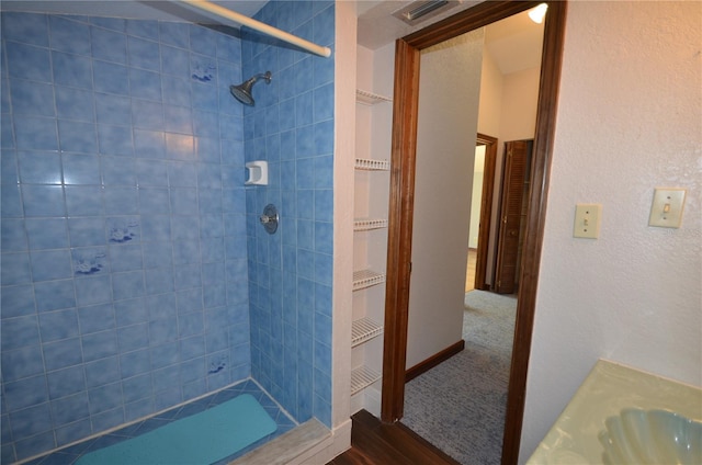 bathroom with tiled shower, vanity, and hardwood / wood-style flooring