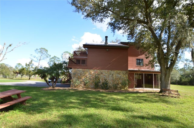 back of property featuring a balcony and a lawn