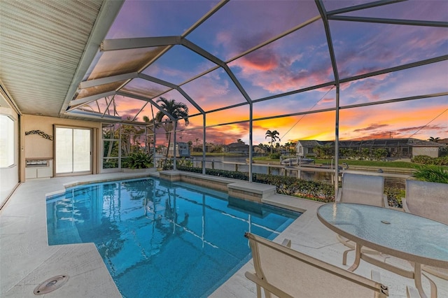 pool at dusk with a patio area and a lanai