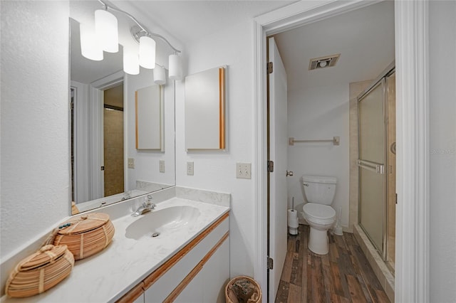 bathroom with hardwood / wood-style floors, vanity, toilet, and a shower with shower door