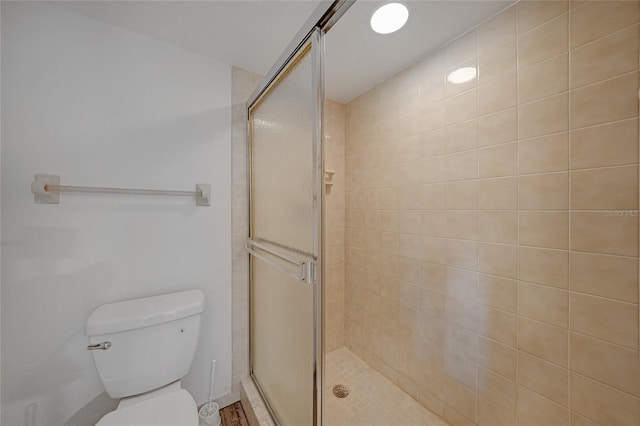 bathroom featuring toilet and a shower with door