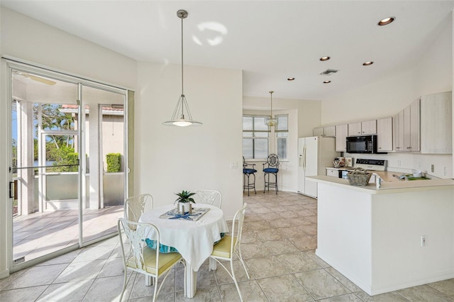 kitchen with kitchen peninsula, white appliances, and decorative light fixtures