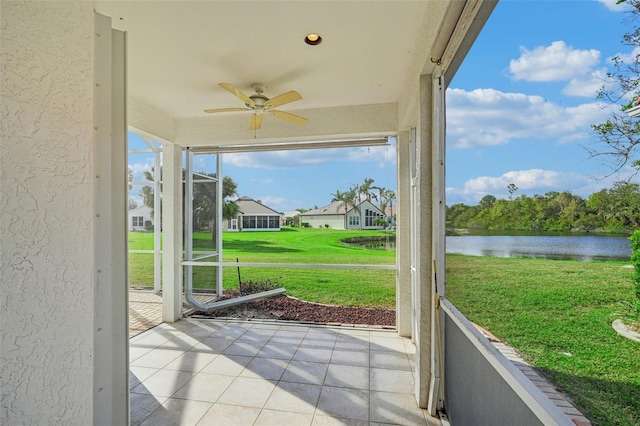 unfurnished sunroom with ceiling fan and a water view