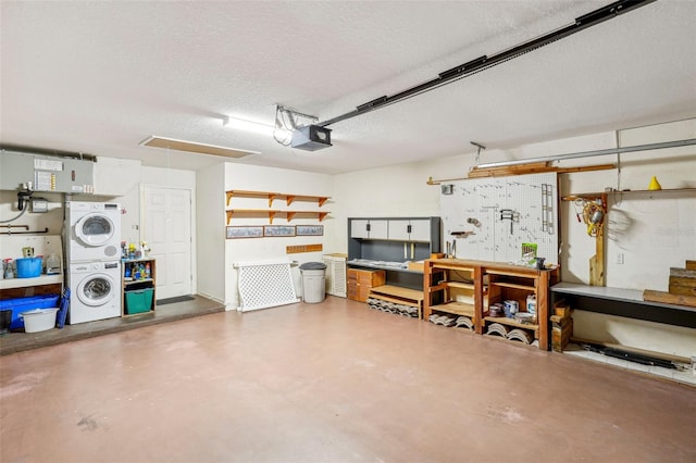 garage featuring a workshop area, a garage door opener, and stacked washer / drying machine