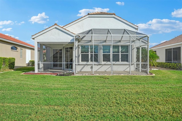 back of house featuring glass enclosure and a yard