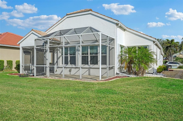 back of property featuring a lanai and a lawn