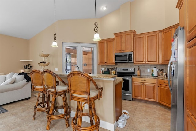 kitchen with light stone countertops, appliances with stainless steel finishes, backsplash, a breakfast bar, and decorative light fixtures