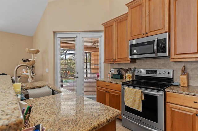 kitchen with decorative backsplash, appliances with stainless steel finishes, light stone counters, sink, and light tile patterned floors