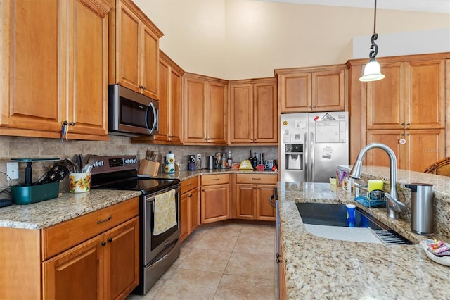 kitchen with light stone countertops, sink, hanging light fixtures, stainless steel appliances, and light tile patterned floors