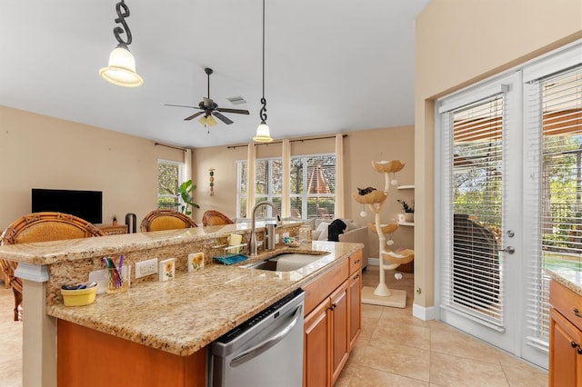 kitchen featuring decorative light fixtures, stainless steel dishwasher, a center island with sink, and sink