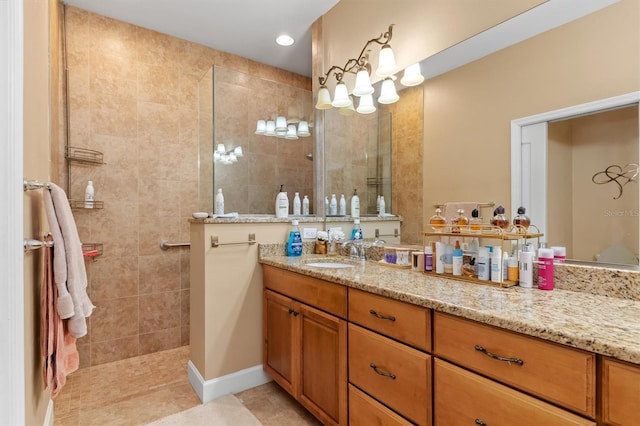 bathroom with tile patterned flooring, a tile shower, and vanity