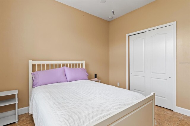 tiled bedroom with ceiling fan and a closet