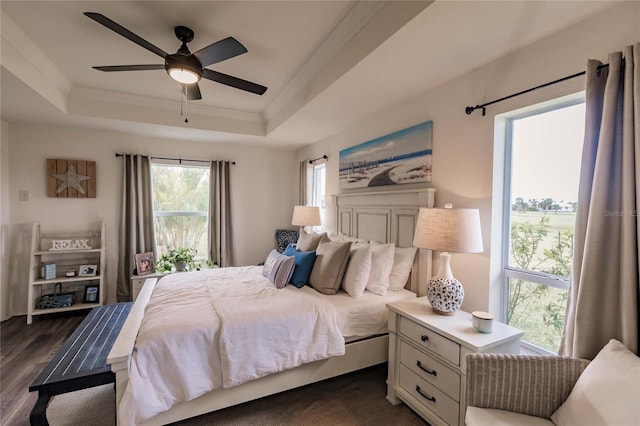 bedroom featuring a tray ceiling, ceiling fan, crown molding, and dark wood-type flooring