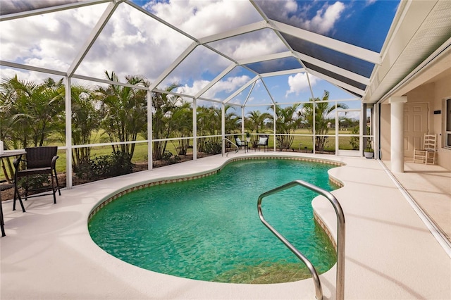 view of pool with glass enclosure and a patio