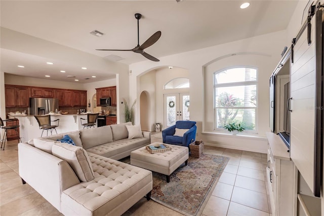 living room featuring french doors, a barn door, light tile patterned floors, and ceiling fan