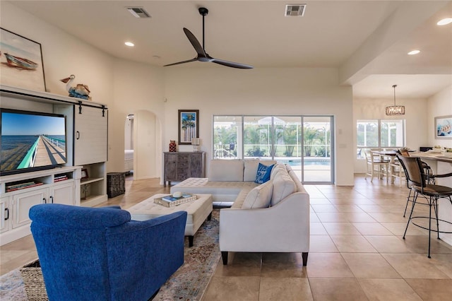 living room with light tile patterned floors, ceiling fan with notable chandelier, and a healthy amount of sunlight