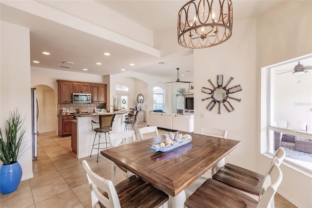 tiled dining room featuring ceiling fan with notable chandelier