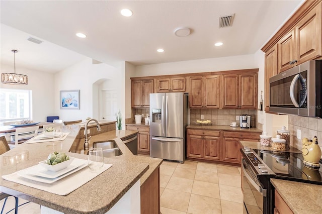 kitchen featuring a spacious island, sink, hanging light fixtures, appliances with stainless steel finishes, and a chandelier