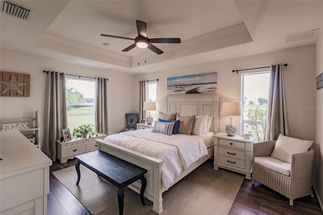 bedroom with dark hardwood / wood-style flooring, a tray ceiling, and ceiling fan