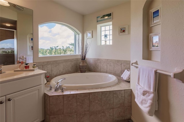 bathroom featuring vanity and tiled tub