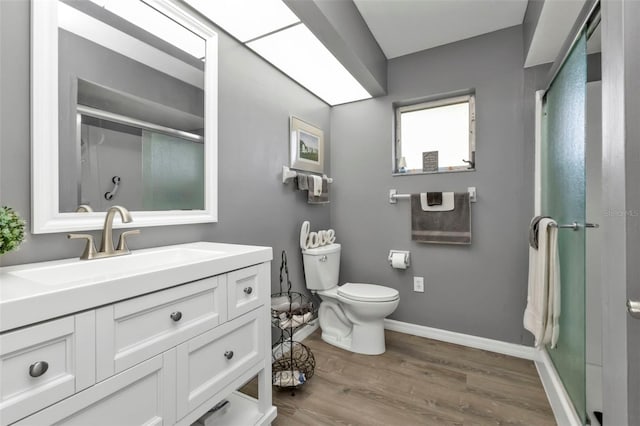 bathroom with vanity, toilet, a shower with shower door, and wood-type flooring