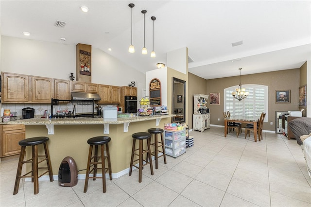 kitchen featuring light stone counters, a kitchen bar, hanging light fixtures, and a chandelier