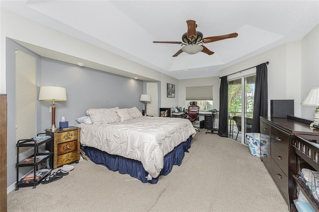 carpeted bedroom featuring access to outside, a raised ceiling, and ceiling fan